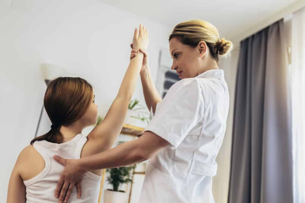 Teen Girl having chiropractic back adjustment. Osteopathy, Physiotherapy, Kinesiology. Bad posture correction. Shoulder injuries